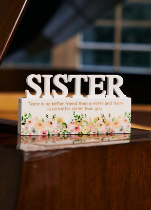 A charming white decorative ornament featuring the word "Sister" with beautiful floral patterns, making it an ideal home decor gift for your sister. The delicate floral design adds a touch of elegance and warmth, making it a perfect gift for birthdays, holidays, or any special occasion. This meaningful ornament symbolizes the love and connection shared between siblings and serves as a reminder of cherished moments. The simple yet elegant white color complements any home decor style, creating a heartfelt and