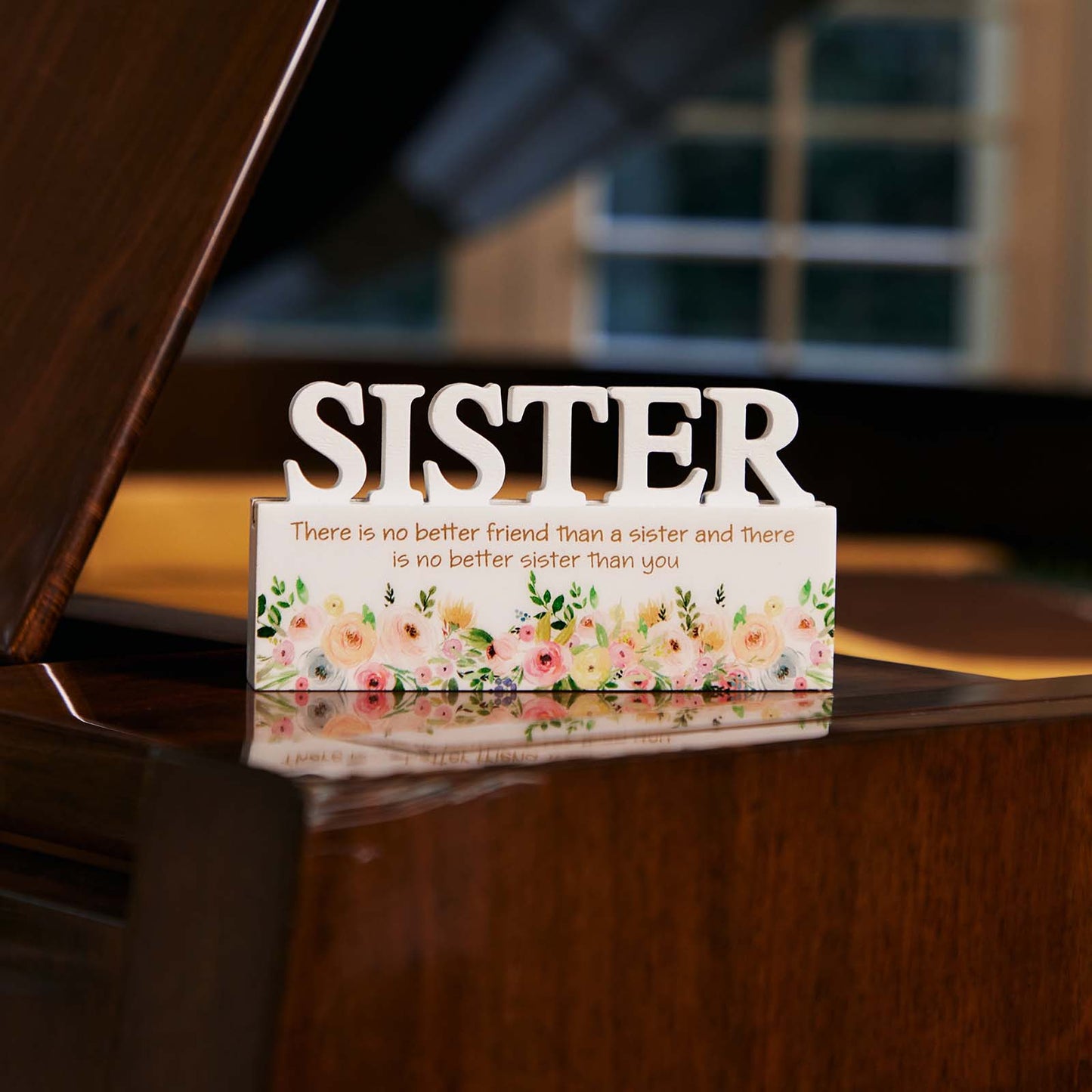 A charming white decorative ornament featuring the word "Sister" with beautiful floral patterns, making it an ideal home decor gift for your sister. The delicate floral design adds a touch of elegance and warmth, making it a perfect gift for birthdays, holidays, or any special occasion. This meaningful ornament symbolizes the love and connection shared between siblings and serves as a reminder of cherished moments. The simple yet elegant white color complements any home decor style, creating a heartfelt and